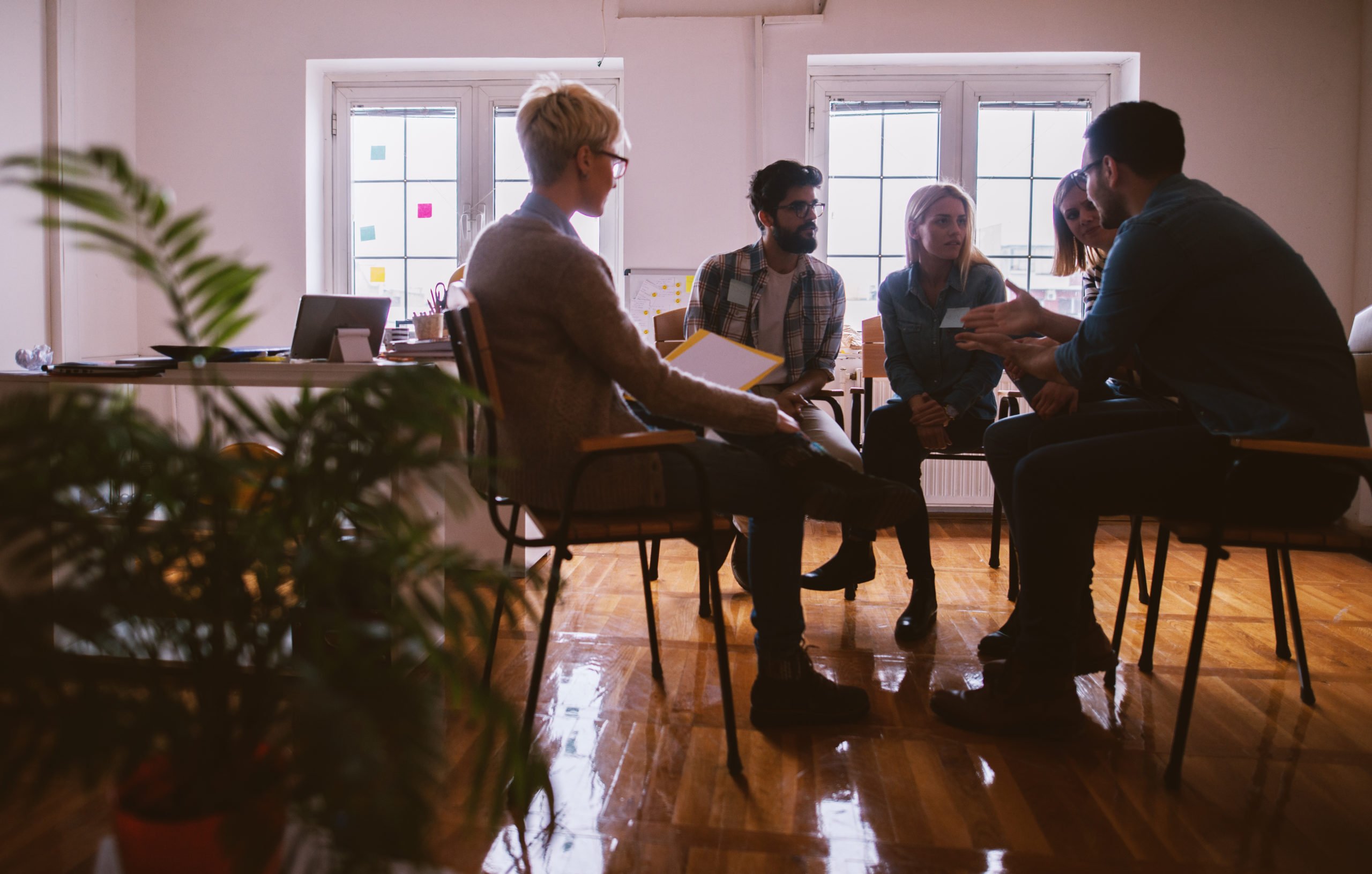 Five people sitting in a dimly lit room having a discussion