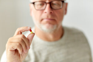 Close up of man holding pill as part of psychiatric services. 