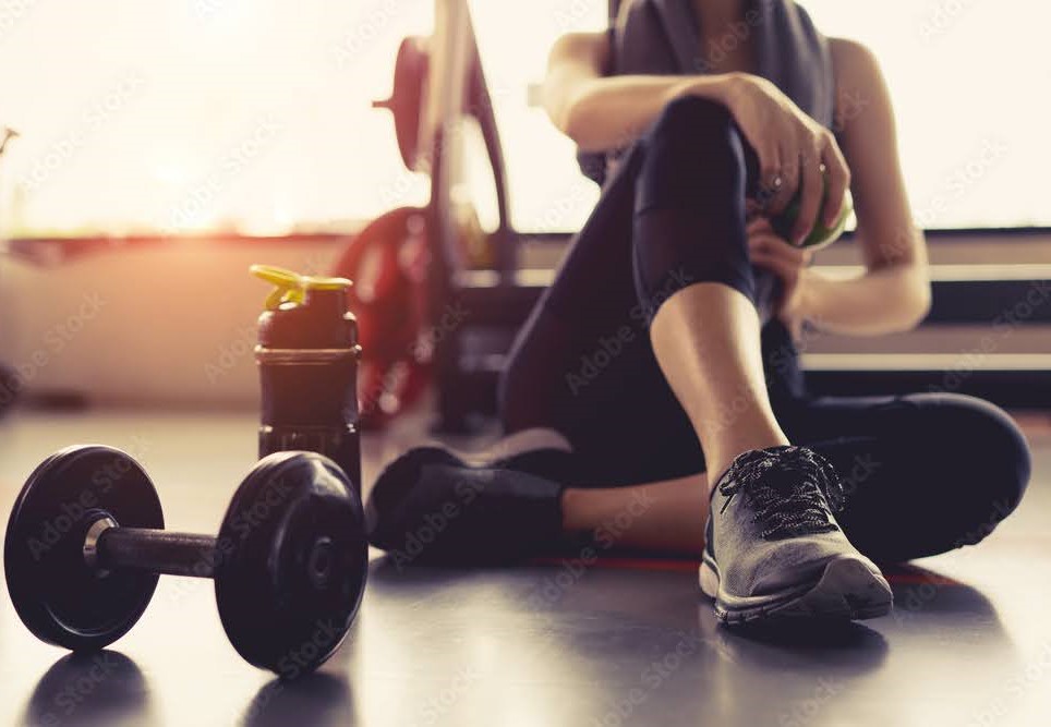 Woman sitting on a gym floor near workout equipment