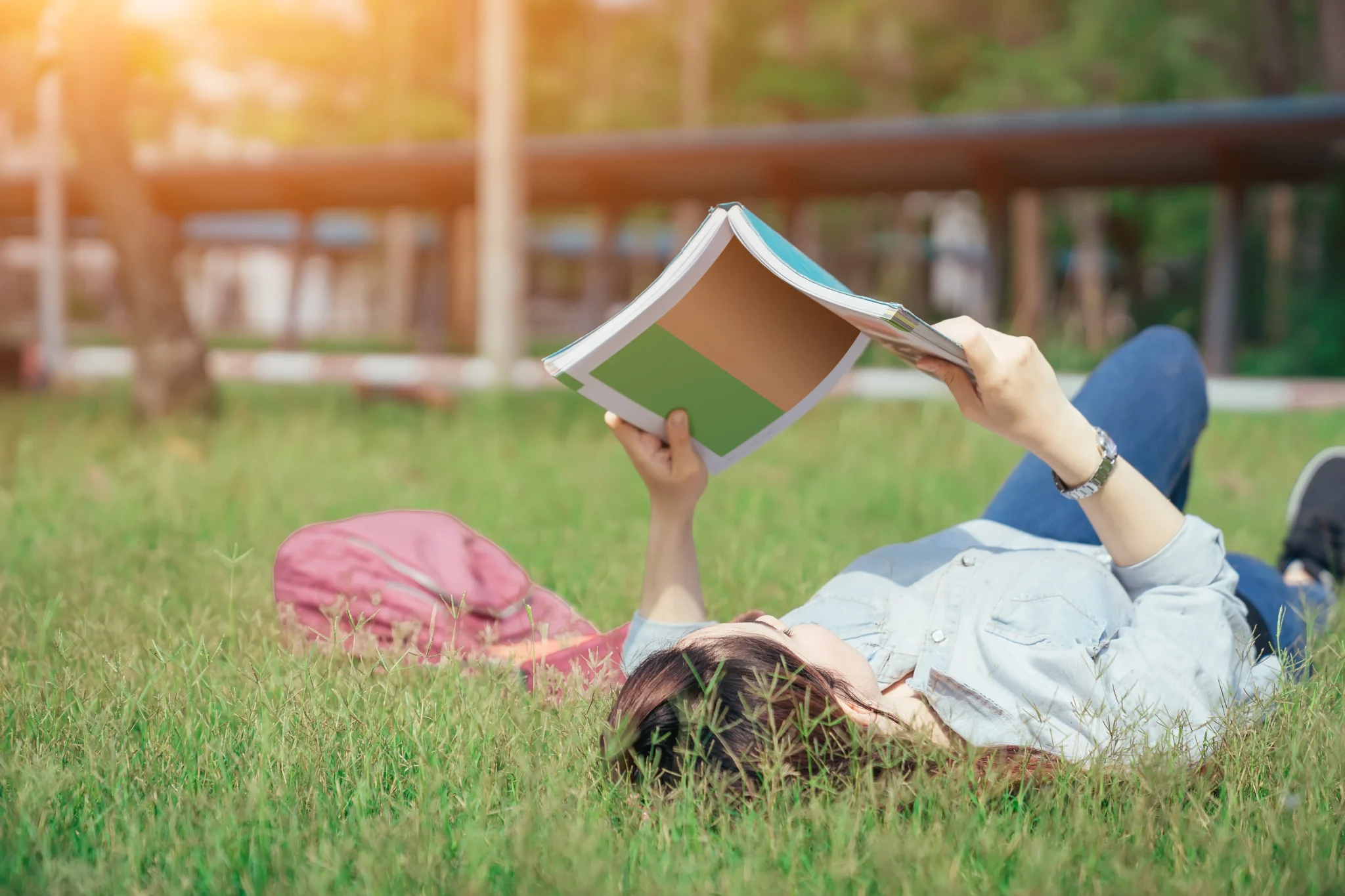 woman lying down in the grass reading